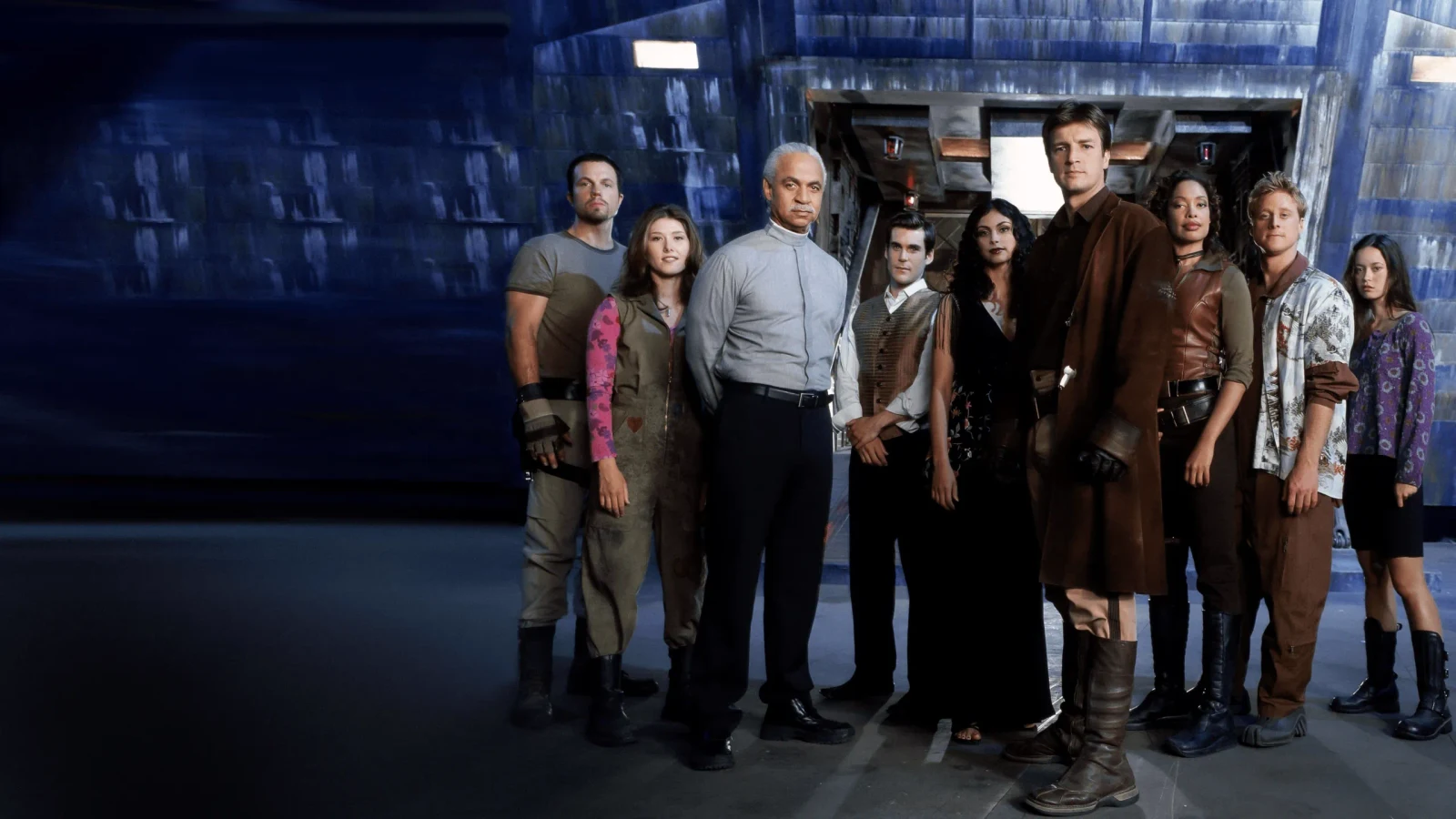 The nine-member Firefly ensemble stands together beside the ship in official series key art.